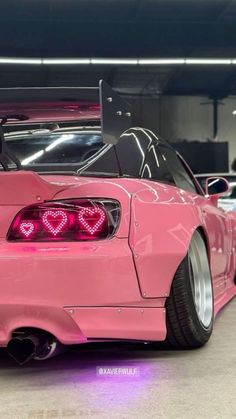 a pink car parked in a parking garage with its hood up and the lights on