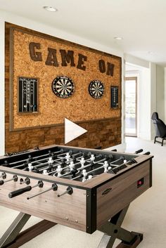 a game room with a foosball table and darts on the wall behind it