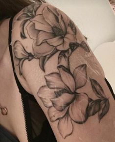 a woman's arm with black and white flowers tattooed on the back of her shoulder