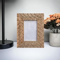 a wooden frame sitting on top of a table next to a vase with flowers in it