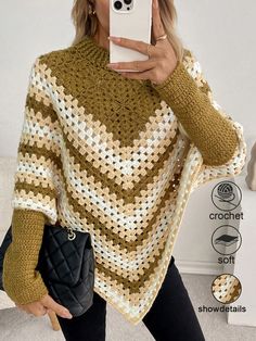 a woman taking a selfie while wearing a crocheted sweater and black pants