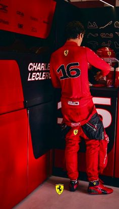 a man standing in front of a red race car with his hands on the door