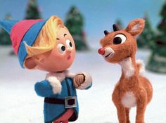 a little boy and a deer in the snow with christmas trees behind them, both looking at each other