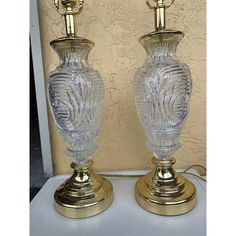 two clear glass vases sitting on top of a white table next to each other