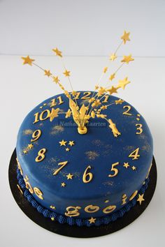 a blue cake decorated with gold stars and a clock on it's side is shown