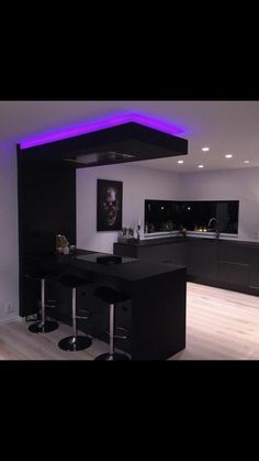 a modern kitchen with black cabinets and purple lighting