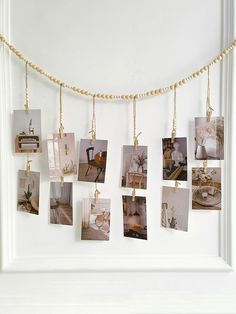 several pictures hanging on a rope in front of a white wall with gold chains and photos attached to it