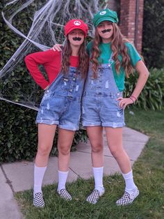 two girls in overalls and hats posing for the camera with their hands on their hips