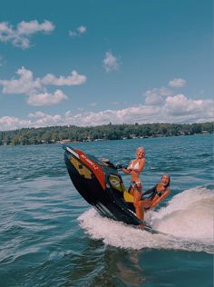 two women riding on the back of a jet ski while being pulled by a boat