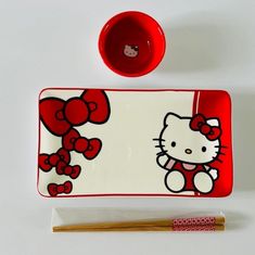 a hello kitty tray with chopsticks next to it on a white table top