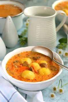 there is a bowl of soup with potatoes and carrots in it on the table