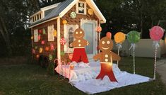 a small house made out of gingerbreads and other decorations in the yard at night