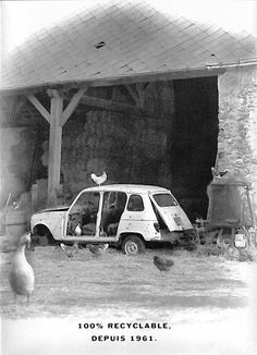 an old black and white photo of a car in front of a barn with chickens