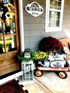 a wooden wagon filled with flowers sitting on top of a porch next to a door