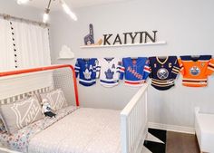 a baby's room with hockey jerseys hanging on the wall and a crib