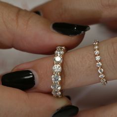 two women's hands with black fingernails and rings on their fingers, one holding a diamond ring