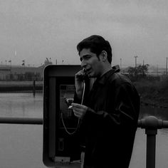 a man talking on a cell phone while standing next to a water way with a river in the background