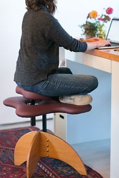 a woman sitting at a desk with her laptop on top of the chair and looking down