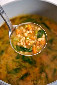 a spoon full of soup with beans and spinach