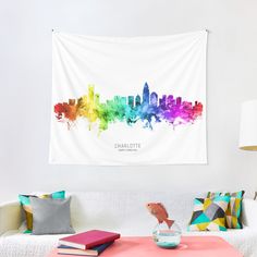 a living room with a white couch and colorful city skyline tapestry hanging on the wall