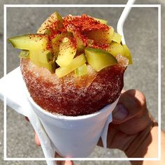 a person holding an ice cream cone with fruit on top