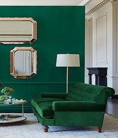 a living room with green walls and two mirrors on the wall, one sitting on a coffee table