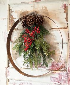 a wreath with berries and pine cones hanging on a door