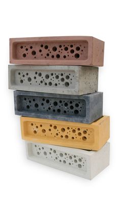 four different colored concrete blocks stacked on top of each other, with holes in the middle