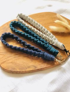 three braided bracelets sitting on top of a wooden cutting board next to feathers