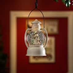 a snow globe ornament hanging from a tree in front of a red wall