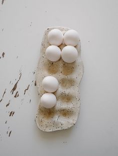 four eggs in a carton on top of a piece of paper with black speckles