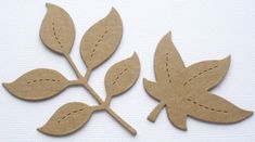 two pieces of cardboard cut out to look like leaves with stitching on the edges