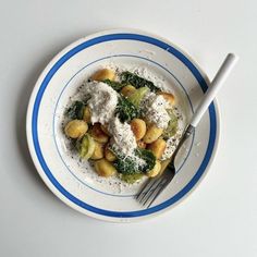 a white and blue plate topped with pasta and broccoli next to a fork