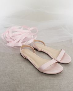 a pair of pink shoes sitting on top of a white cloth covered floor next to a ribbon