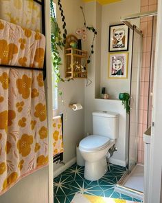 a white toilet sitting inside of a bathroom next to a shower curtain and rugs