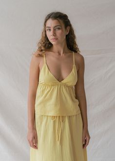 Brighten your days with our Mökki Halter Top in Sunlight, a dreamy pastel yellow that radiates joy. Hand-dyed by artisans in Bali, each top is unique, showcasing the beauty of its creation. Made from soft, breathable Cotton Slub, this top is perfect for embracing the warmth of summer. This feminine halter top features adjustable multifunctional straps for effortless elegance, which can be tied around the neck or attached to two hidden loops at the back, allowing you to style it any way you choos Yellow V-neck Top For Loungewear, Natural Dye Tops For Spring Beach, Yellow Summer Tops For Loungewear, Yellow Linen Summer Tops, Yellow Summer Top For Daywear, Yellow Summer Tops For Daywear, Yellow Linen Tops For Spring, Yoga Flare Pants, Fabric Journals