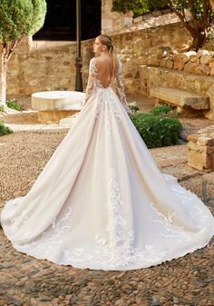 a woman in a wedding dress is standing on the cobblestone road and looking back