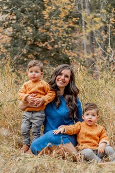 a woman and two children sitting in tall grass