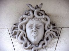 a statue of a woman's head with snakes around it on the side of a building