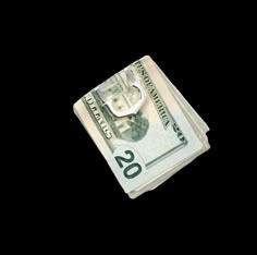 a stack of twenty dollar bills on a black background with the letter u in the middle