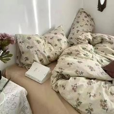 an unmade bed with flowers and books on the bottom shelf in front of it