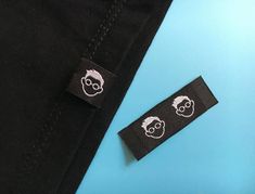 a pair of black pants with white patches on the side and one has an image of a man's head