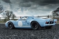 a blue sports car parked on top of a gravel field