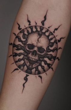 a skull and sun tattoo on the arm