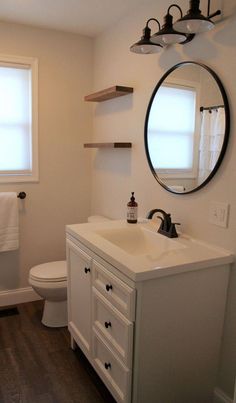 a bathroom with a sink, mirror and toilet in it's corner next to a window