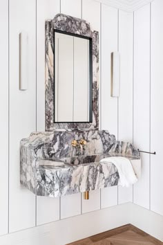 a marble sink and mirror in a white bathroom with wood flooring on the walls