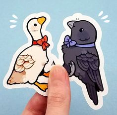 a hand holding up two stickers with ducks and geese on them in front of a blue background