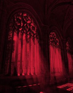 red light shining through the windows in an old building with columns and arches on either side