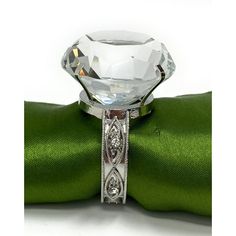 a diamond ring sitting on top of a green satin ribbon with a bow around it