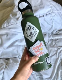 someone is holding a green water bottle with stickers on it that says support your neck